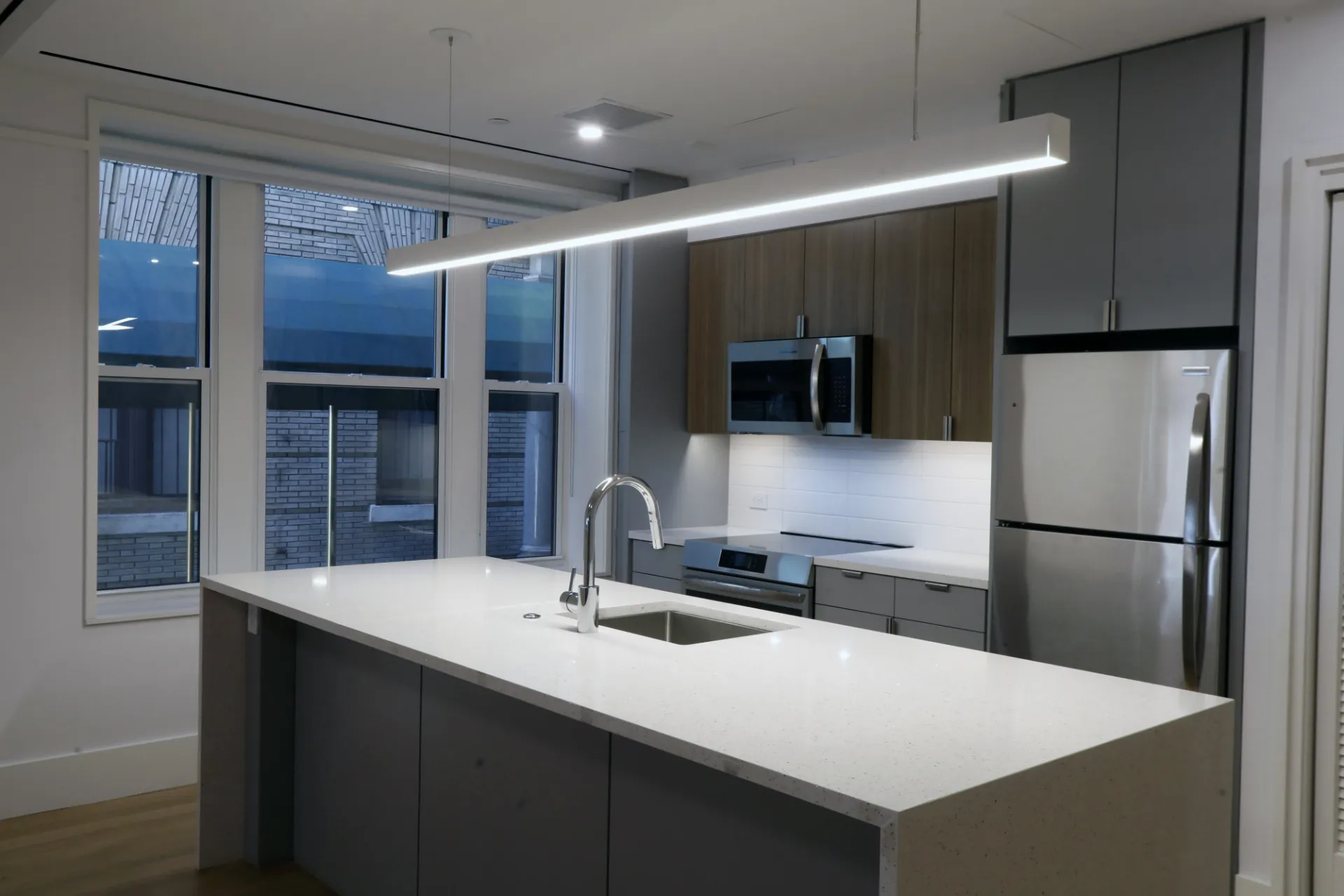 A newly renovated kitchen with gray and wood cabinets and a white and gray kitchen island.