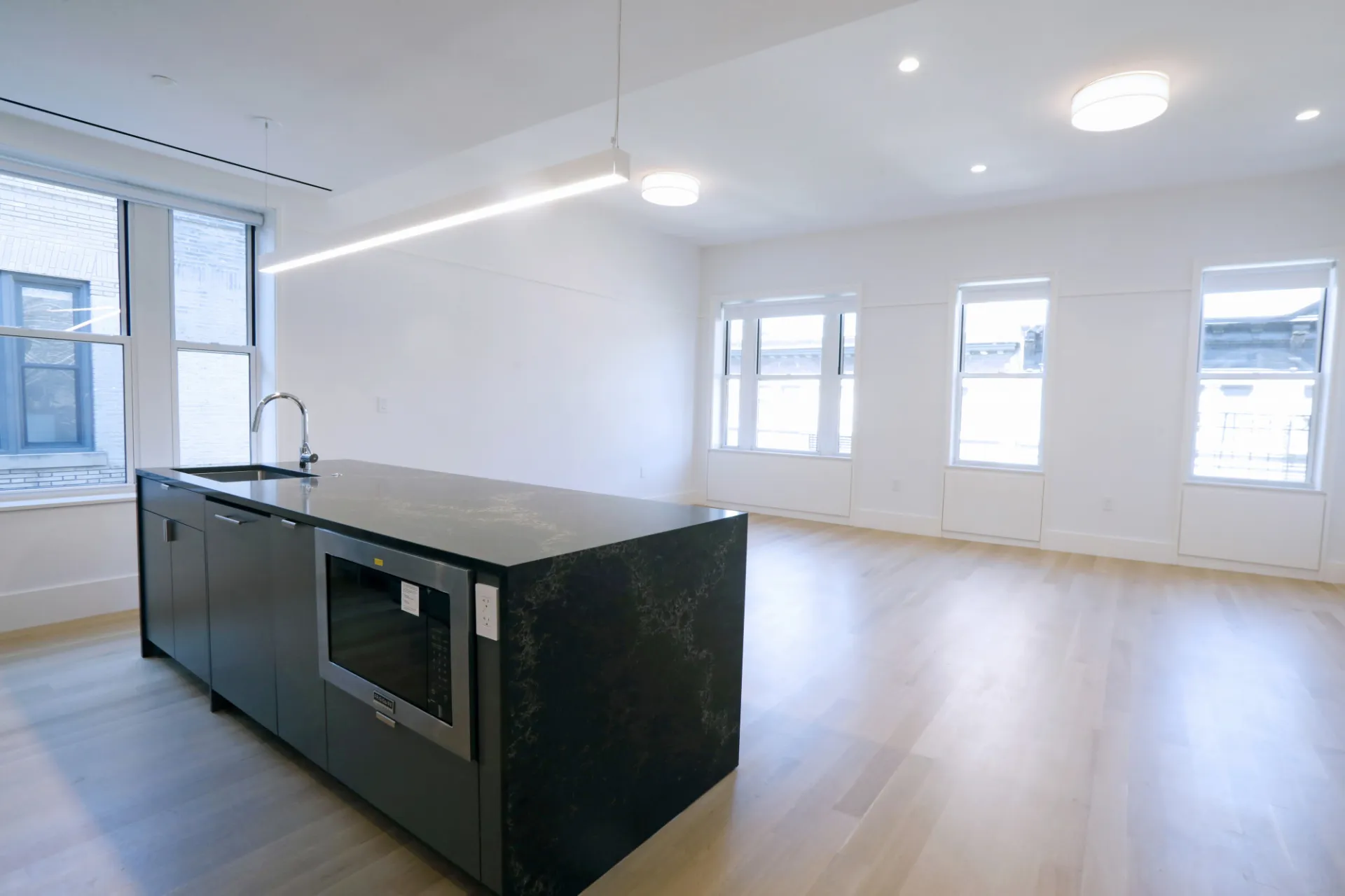 A renovated apartment at 518 W. 111th Street with a dark gray and gold accent granite kitchen island that overlooks a living room.