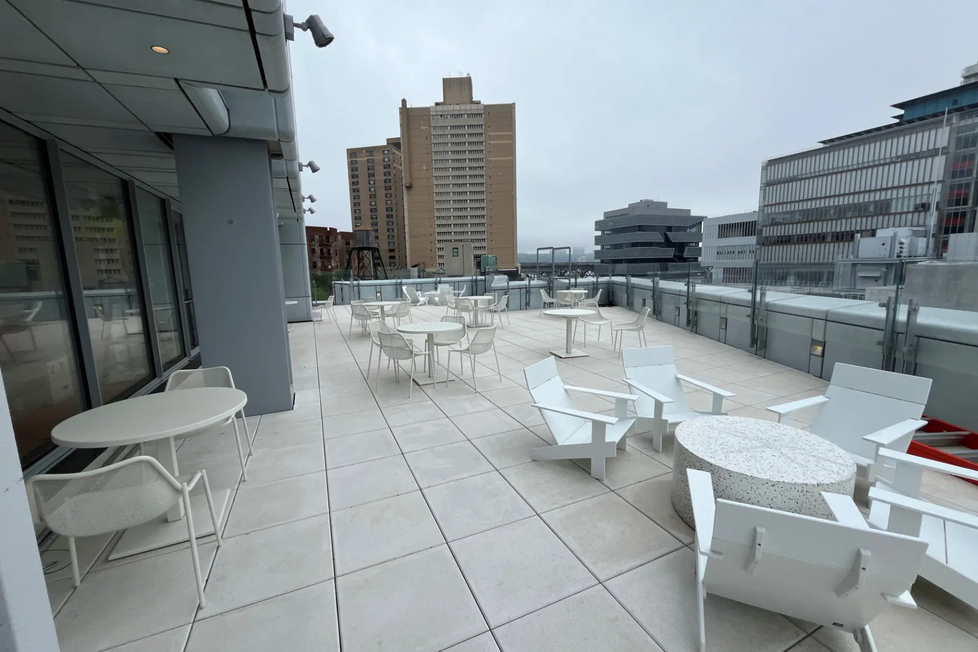 An outdoor terrace with white furniture overlooking Columbia Business School, Lenfest Center for the Arts, and Jerome L. Greene Science Center.