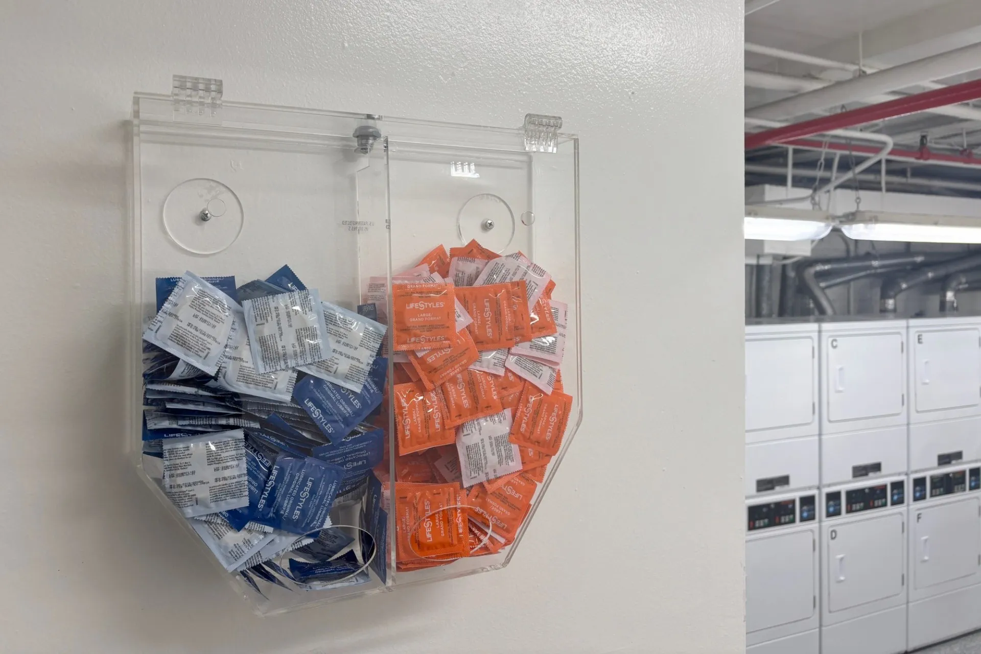 A dispenser with condoms located in a residence hall laundry room.