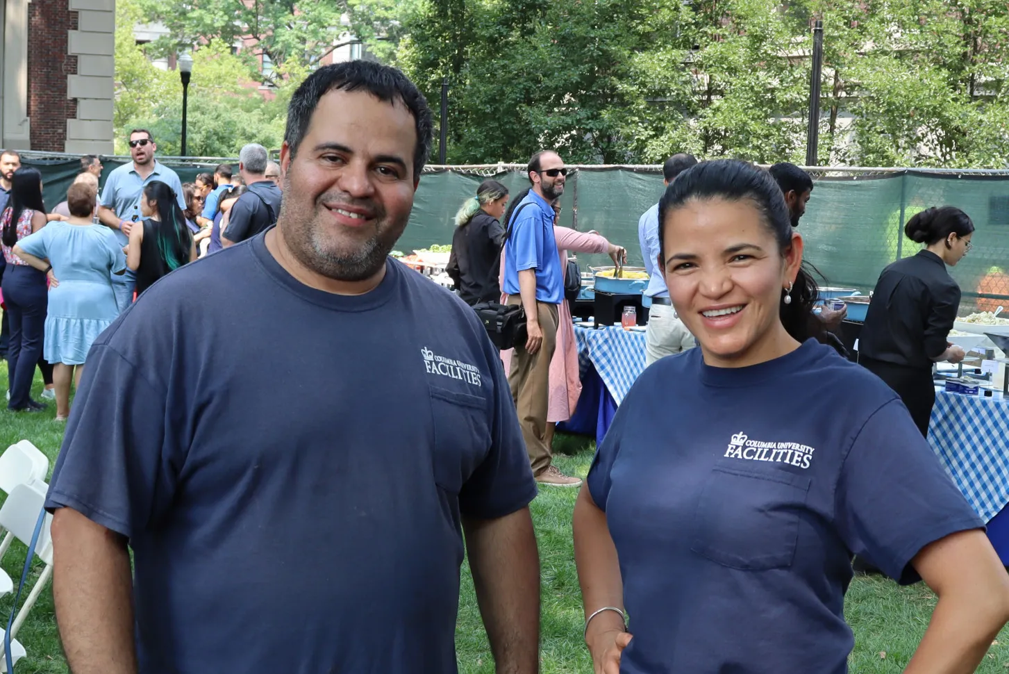 Two Facilities and Operations employees stand together at an event.