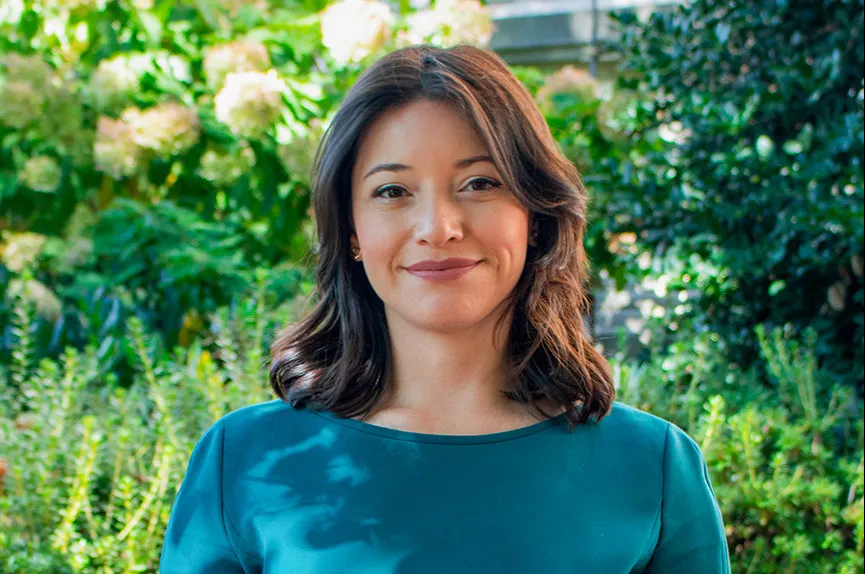 Lorena Prosco smiles in front of a green space.