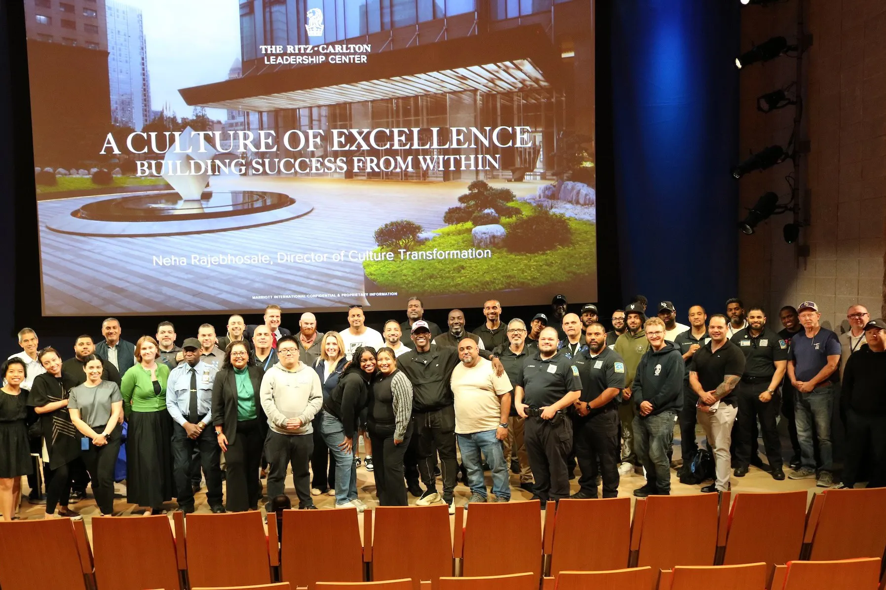 Group in front of screen displaying 'The Ritz-Carlton Leadership Center' and 'A Culture of Excellence' with Neha Rajehunsale."