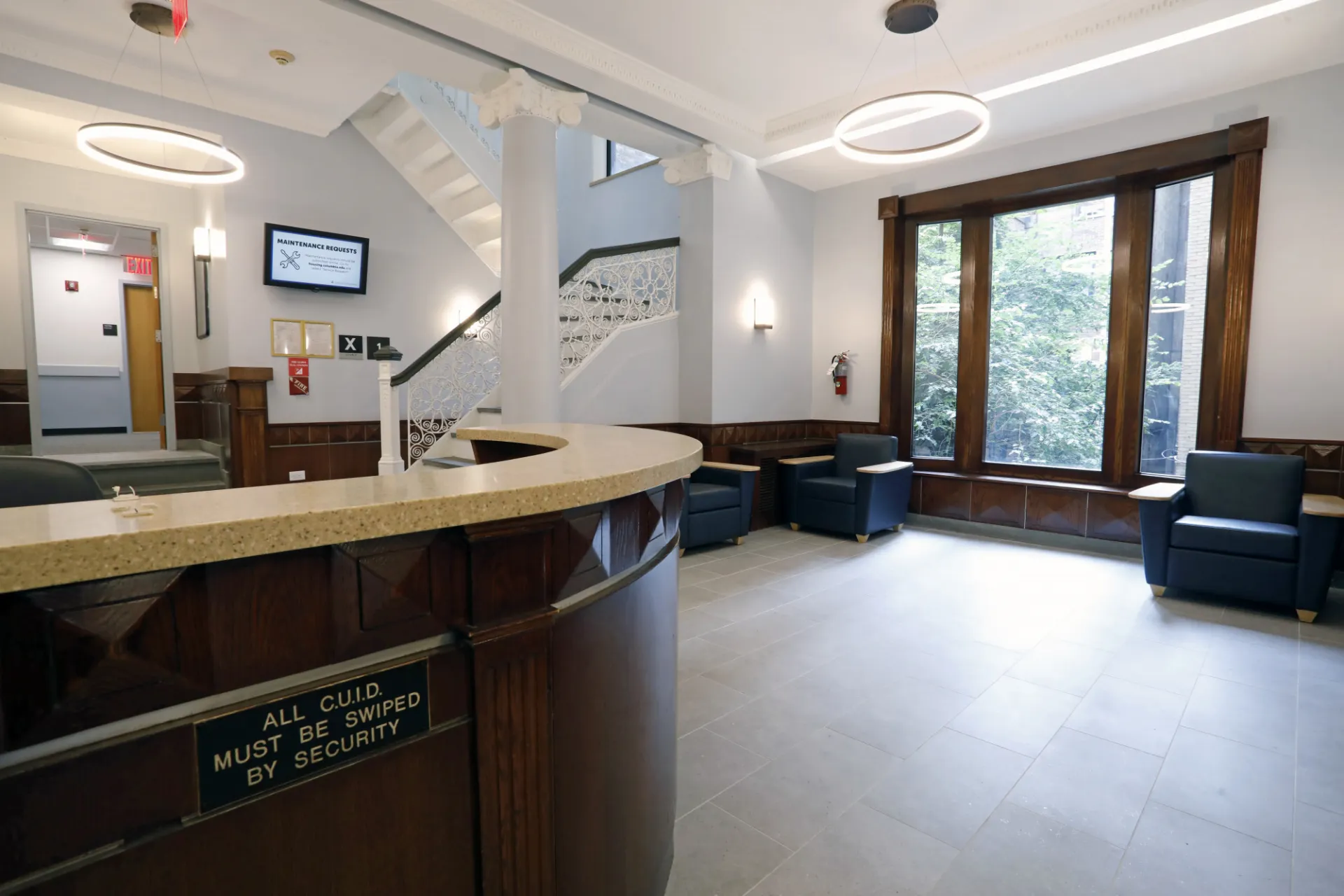 The River Hall lobby with a wood security desk, wood accents, white walls, and blue lounge furniture.