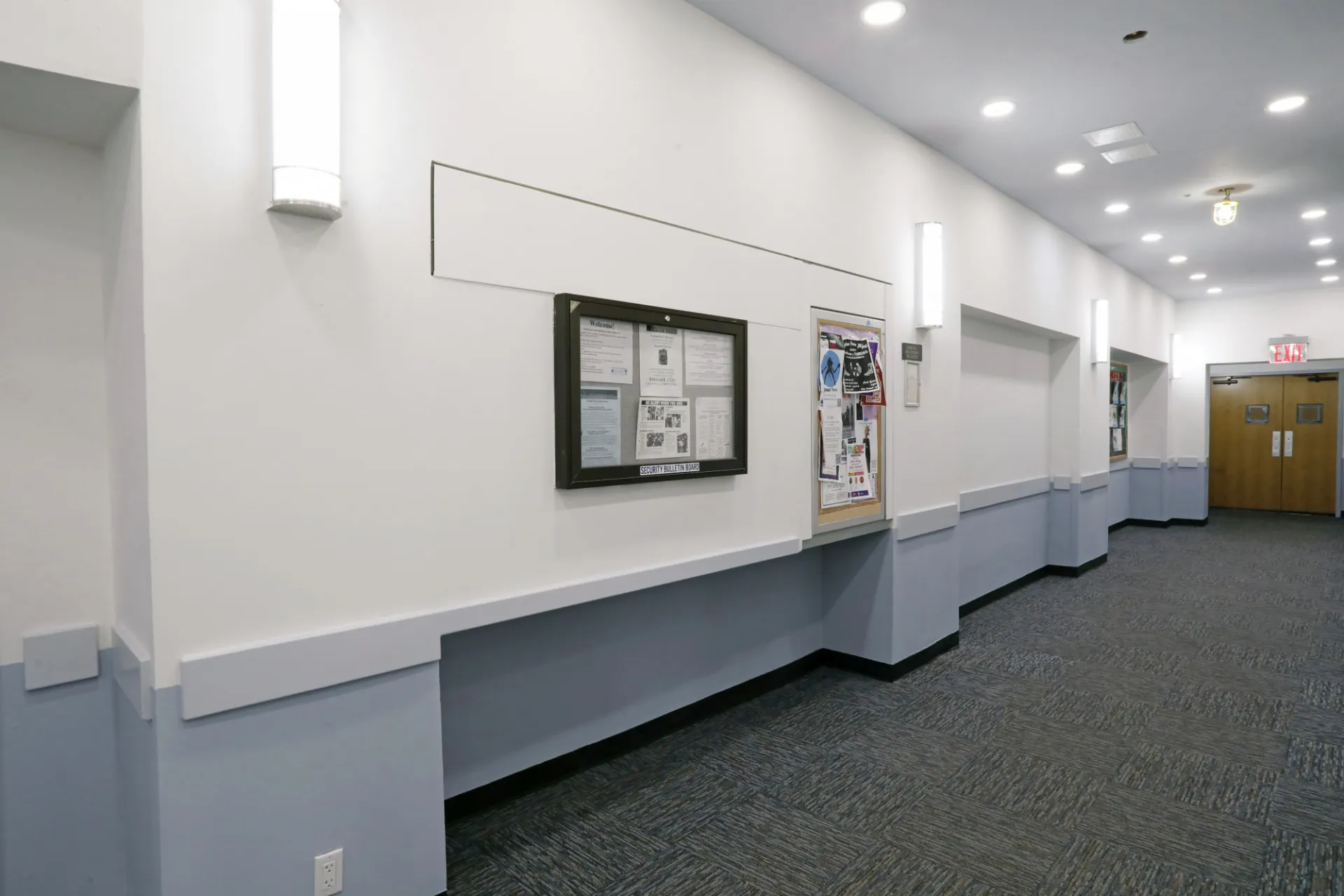 A refreshed corridor in Hogan Hall with white and light blue walls and gray carpeting.