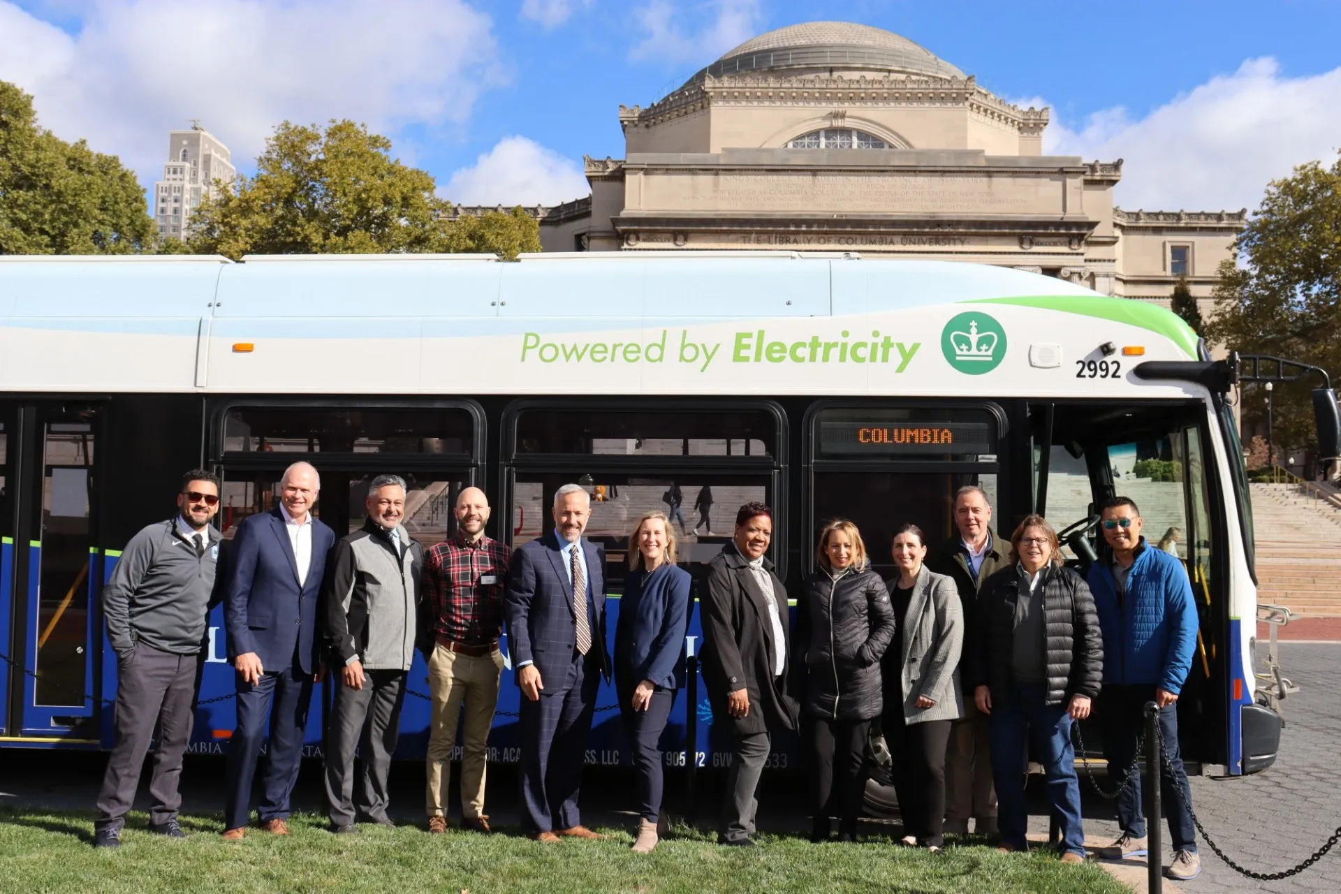 Members of Columbia's Office of Sustainability and Facilities and Operations stand in front of one of the University's electric buses on College Walk