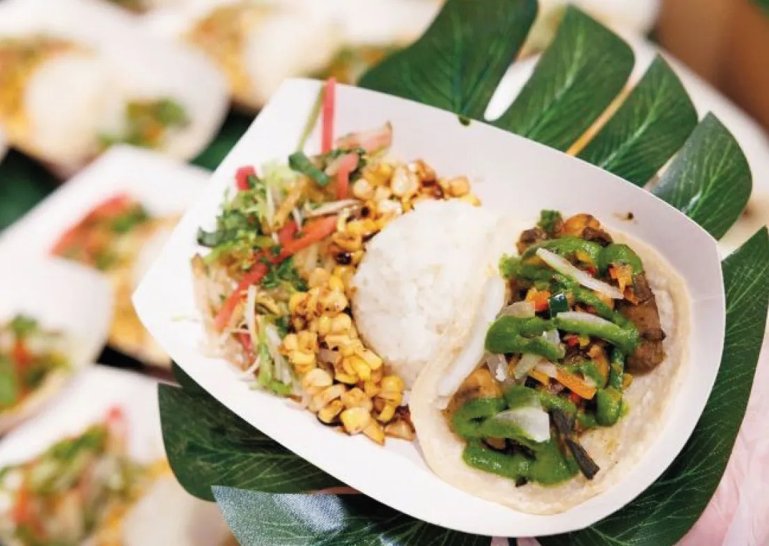 A plate of plant-based food including a taco, rice, and corn.